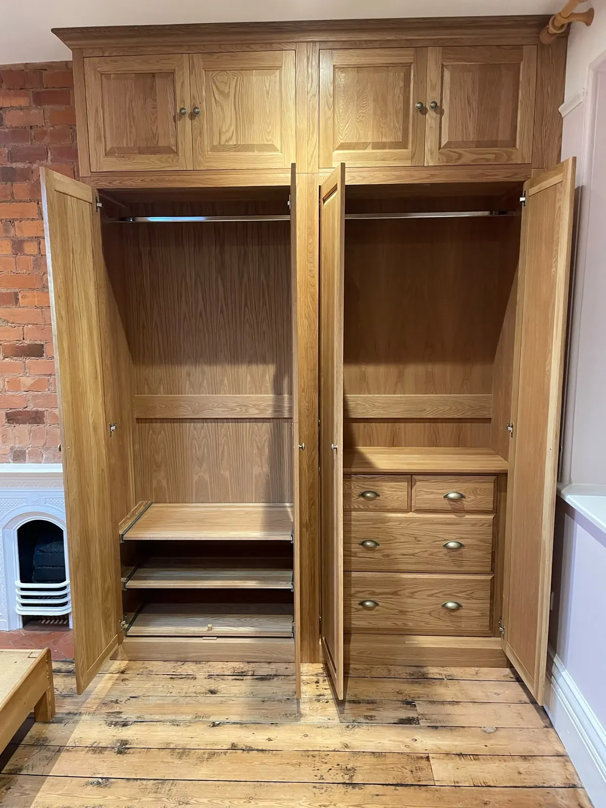 Oak fitted wardrobe with doors open, showing hanging rails, shelves and a set of drawers