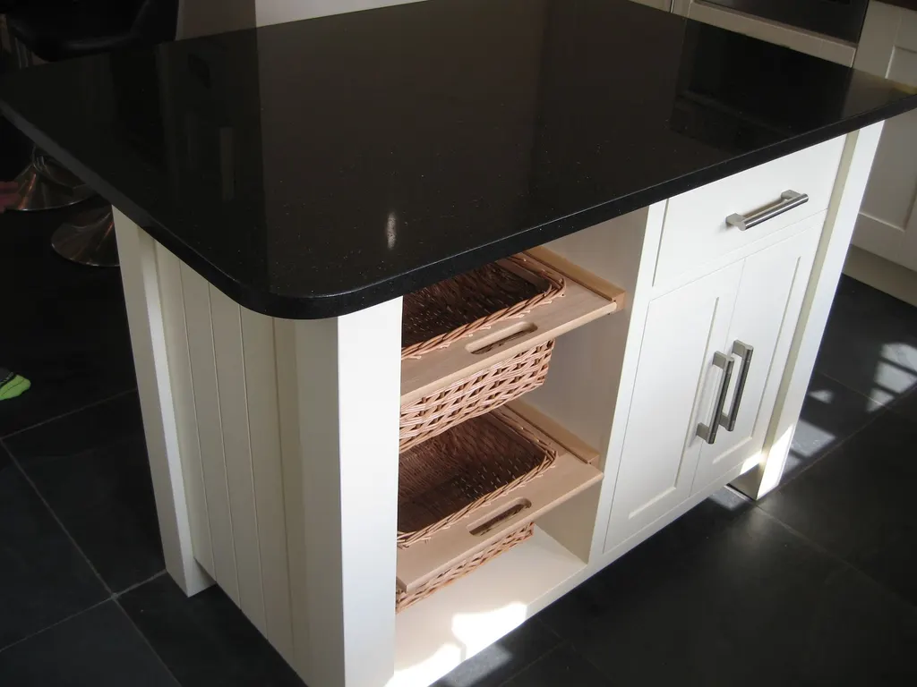 Painted kitchen island unit with wicker basket drawers and a black worktop