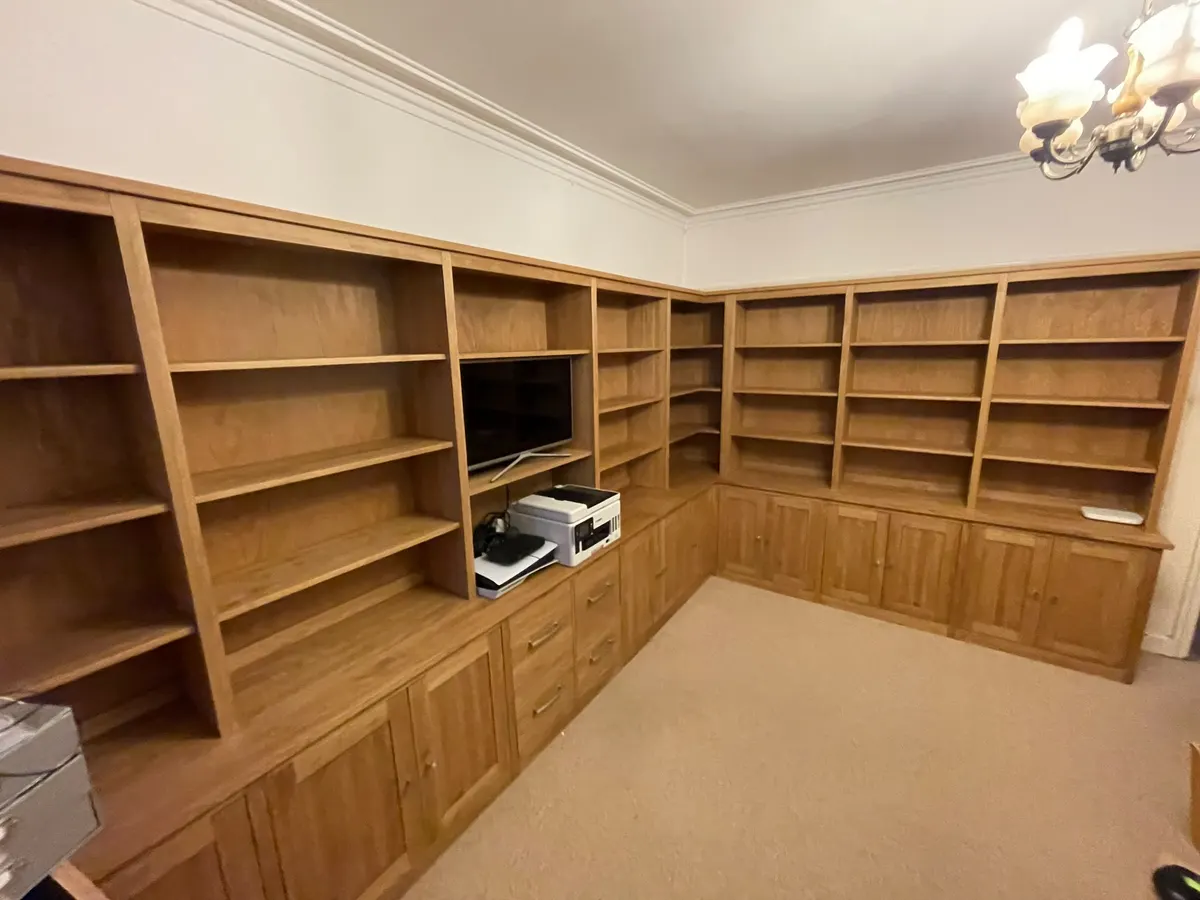 Timber fitted bookcases and cupboards wrapping around the corner of a study